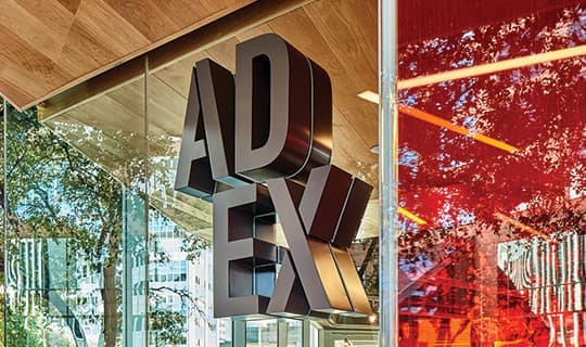 AD EX dimensional signage identity mounted to glass facade of architecture.