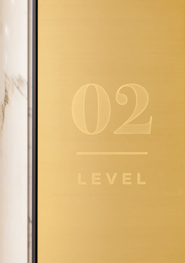 PacMutual Building gold level identity signage on marble wall.